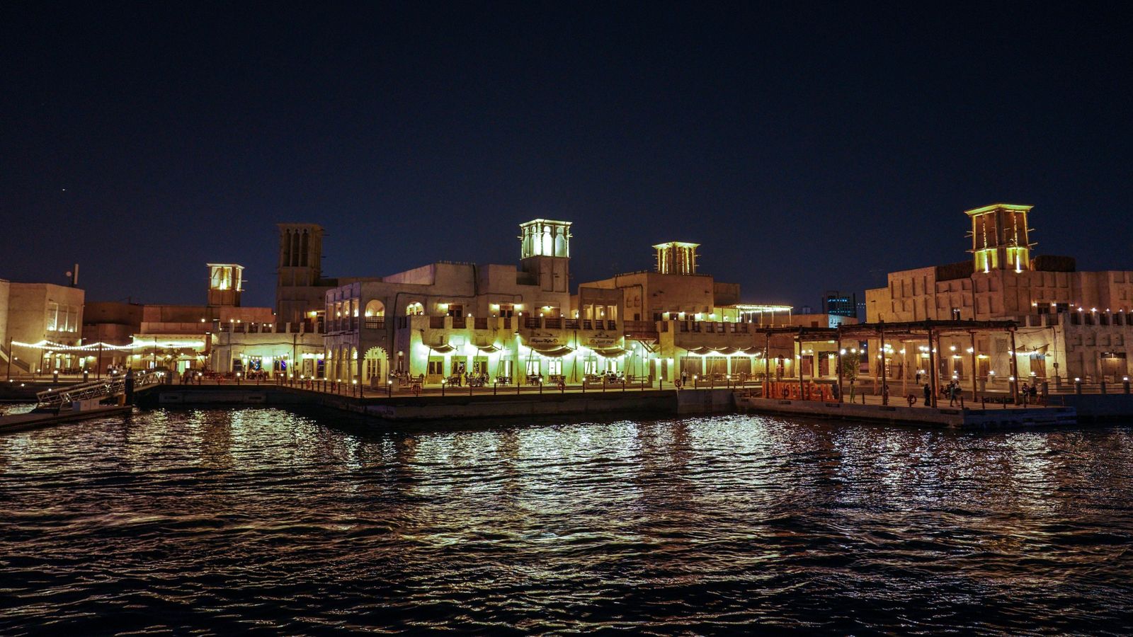 Dubai Creek kıyısında geleneksel mimari ve rüzgâr kuleleri, gece manzarası